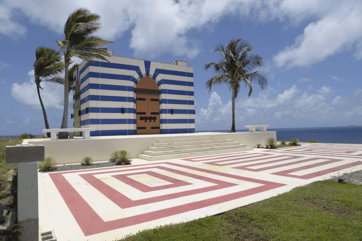 efta00002940 temple blue and white striped building with a red and white labyrinth in front set against a tropical backdrop of palm trees and the ocean under a bright sky