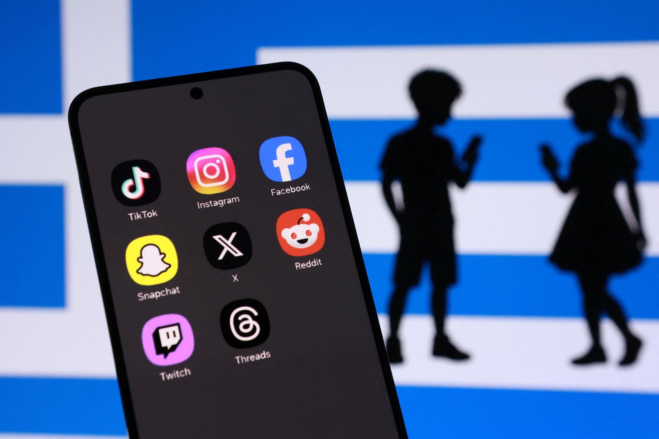 Illustration shows Greek flag, social media app icons and children's silhouettes Προς απαγόρευση τα social media στην Ελλάδα για τους κάτω των 15